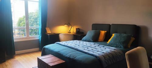 una camera da letto con un letto con lenzuola blu e una finestra di Suite parentale avec grand bureau a Saint-Maur-des-Fossés