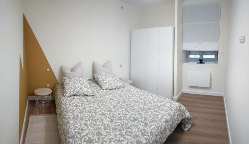 - une chambre avec un lit et une couette blanche dans l'établissement T2 hyper centre LONS LE SAUNIER, à Lons-le-Saunier
