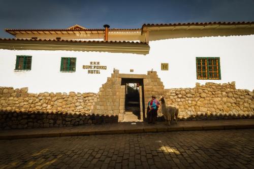 a person and a horse standing in front of a building at Hotel Rumi Punku in Cusco