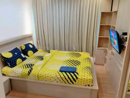 1 dormitorio con 1 cama con edredón amarillo en Ryan dan Ilham Apartemen, en Dadap