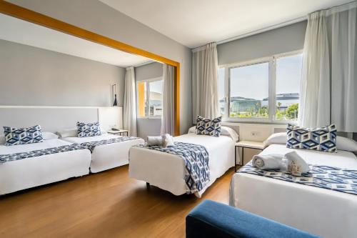 um quarto de hotel com três camas e um sofá em Hotel Beleret em Valência