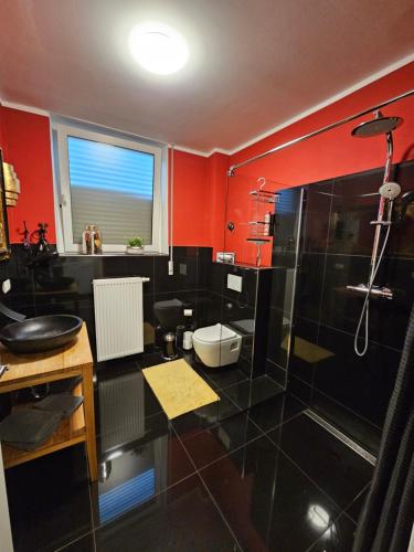 a bathroom with red walls and a shower and a sink at Bismarck-Apartment in Kaiserslautern