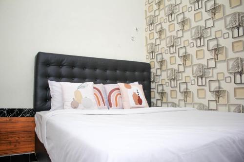 a bedroom with a bed with white sheets and pillows at Capital O 2258 Santana Syariah Guest House in Solo