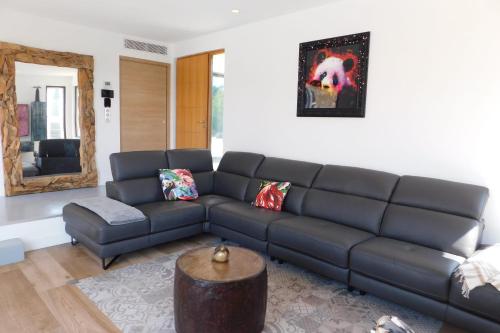 ein Wohnzimmer mit einem schwarzen Sofa und einem Spiegel in der Unterkunft Stunning air-conditioned villa "Ronsard" with swimming pool in Saint-Aygulf