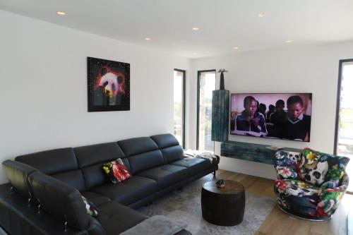 ein Wohnzimmer mit einem schwarzen Sofa und einem TV in der Unterkunft Stunning air-conditioned villa "Ronsard" with swimming pool in Saint-Aygulf
