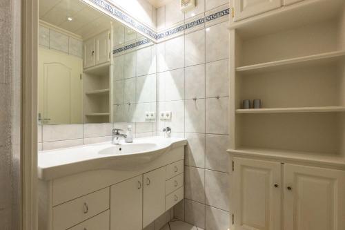 ein weißes Badezimmer mit Waschbecken und Spiegel in der Unterkunft Appartement Kleeblatt in Westerland