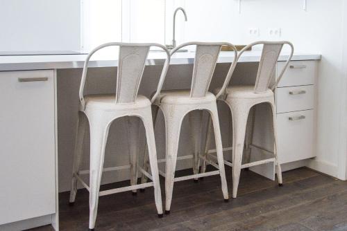 two white bar stools sitting at a kitchen counter at Entre Deux Pays Apartments in Spa