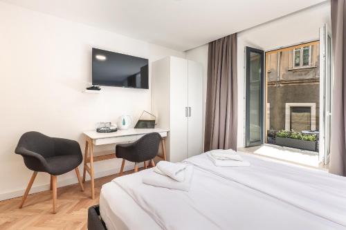 a hotel room with a bed and a desk and a window at Residence INN Rijeka in Rijeka