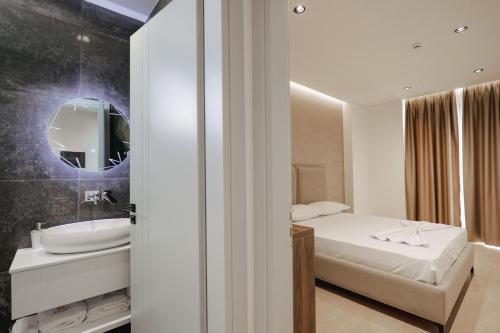 a bedroom with a bed and a sink and a mirror at Sunlight Hotel in Ksamil