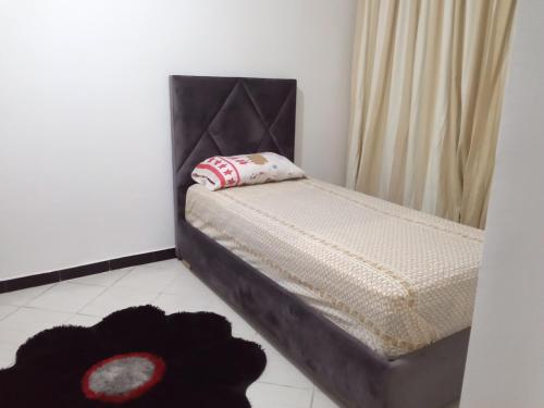 1 cama pequeña con cabecero negro en una habitación en Appartement en Agadir