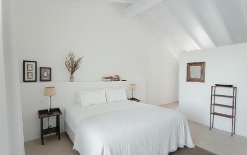 a white bedroom with a white bed and a ladder at Amaria in Aljezur