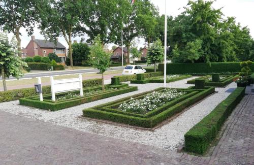a park with a bench and flowers and a street at B&B De Rozenhorst in Baarlo