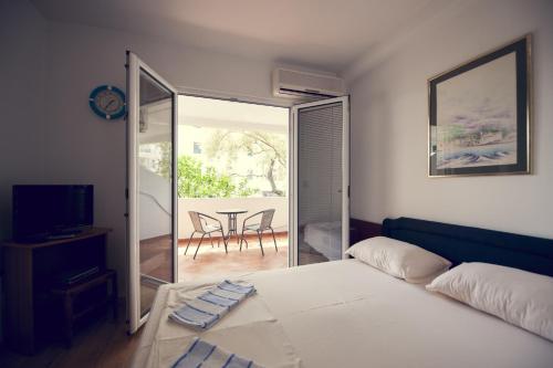 a bedroom with a bed and a balcony with a table at Lyon Apartments in Budva