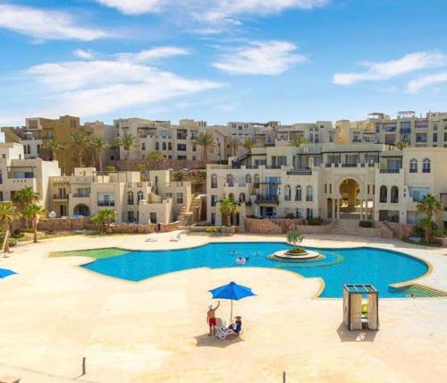 een groep mensen die onder een paraplu bij een zwembad zitten bij Azzurra two-bedrooms apartment at Sahl Hasheesh in Hurghada