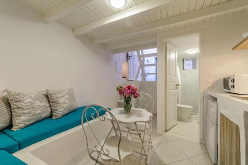 The Bay - Loft apartment Sea & Sunset View في أويا: غرفة صغيرة مع أريكة زرقاء وطاولة مع الزهور