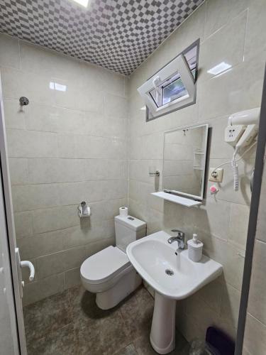 a bathroom with a white toilet and a sink at Junona in Makhinjauri