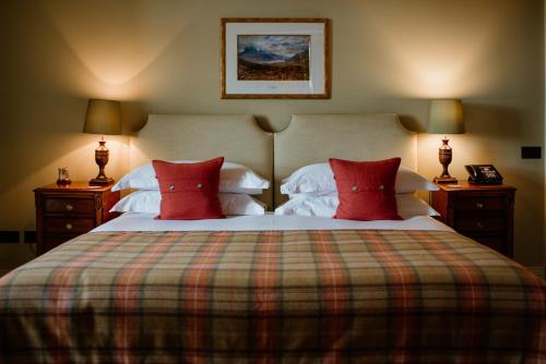 a bedroom with a large bed with red pillows at Links House at Royal Dornoch in Dornoch