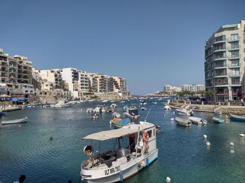 a boat is docked in a river with buildings at Confortable and Quiet Apartment in St. Julian in Tal-Għoqod