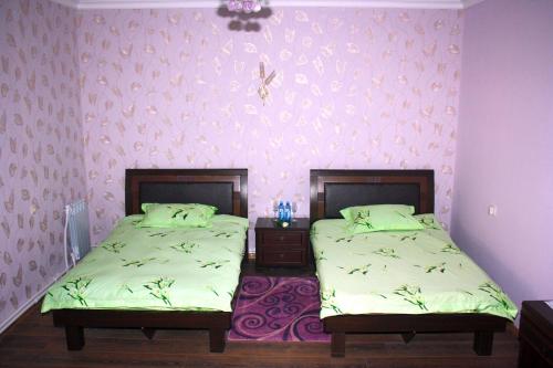 two twin beds in a room with pink walls at Christy Hotel in Goris
