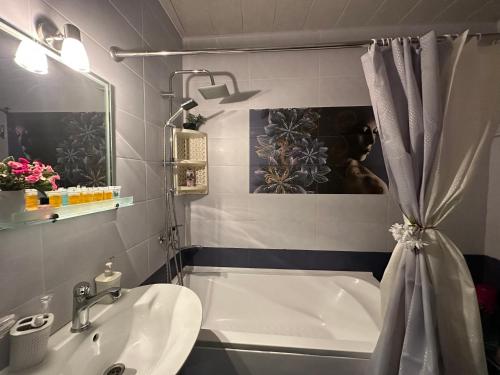 a bathroom with a tub and a sink and a shower curtain at AnnaMari in Tbilisi City