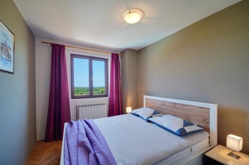 Schlafzimmer mit einem Bett mit lila Vorhängen und einem Fenster in der Unterkunft Antica Suite Apartment in Radmani