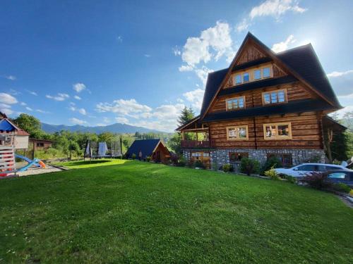 drewniany dom z zielonym trawnikiem przed nim w obiekcie Apartament Zakątek Góralki w Zakopanem