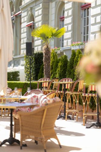 a group of chairs and tables and a palm tree at Grand Hotel National Luzern in Luzern