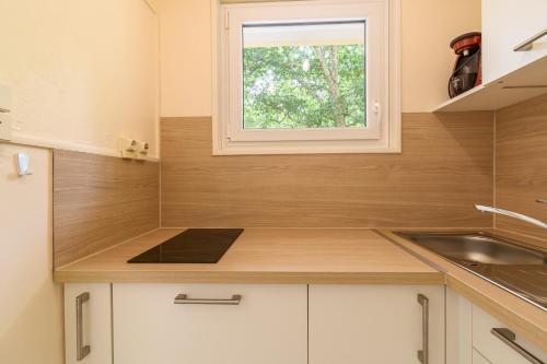 une petite cuisine avec un évier et une fenêtre dans l'établissement Pot de Résine - Appartement à 500m de la plage, à Arcachon