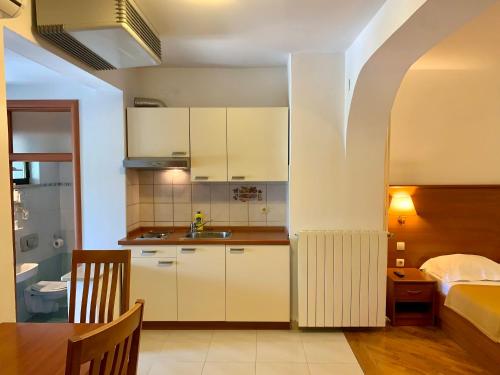 a kitchen with white cabinets and a table and a bed at Gargamelo Pension in Poreč