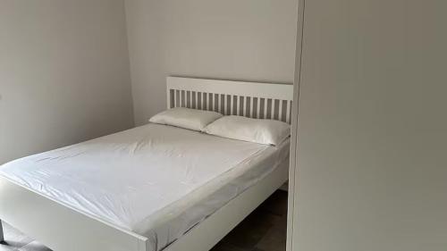 uma cama branca com duas almofadas em cima em Galvani 11 em Parma