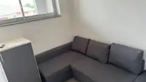 um sofá cinzento num quarto com uma janela em Galvani 11 em Parma