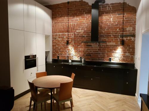 a kitchen with a table and a brick wall at Apartamenty Carskie Koszary in Zamość