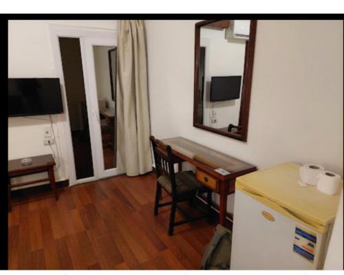 Habitación con escritorio, espejo y mesa. en Salvatore Rooms With Breakfast -Train Station en El Mansurá