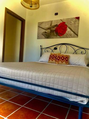 a bedroom with a bed with a red rose on the wall at Camera Villa Sarda Aurora in Elmas