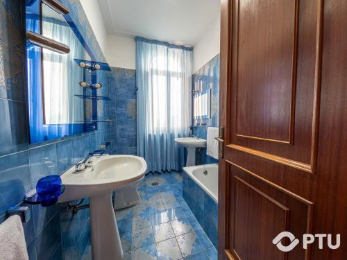 Baño de azulejos azules con lavabo y espejo en PoloTuristicoUmbria Villa del Maestrale, en Perugia