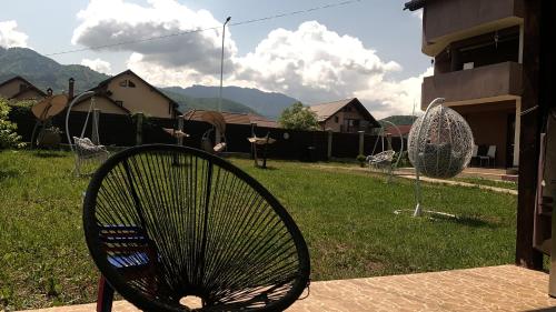 a chair sitting in a yard with a swing at Vila Mik Guesthouse in Săcele
