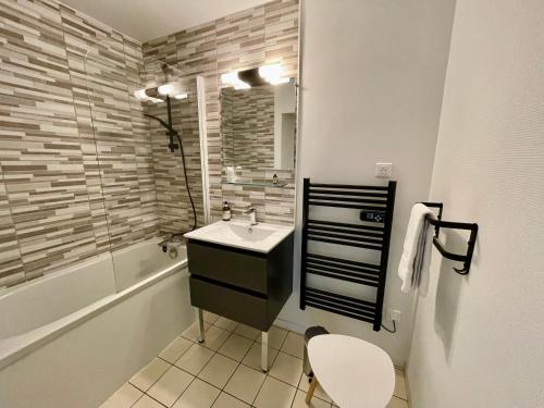 a bathroom with a sink and a bath tub at Hôtel Paris Madrid in Lesperon
