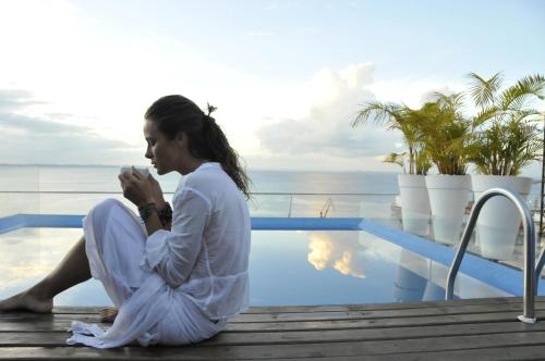 una mujer sentada junto a una piscina en Aram Yamí Boutique Hotel, en Salvador