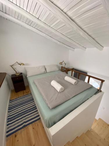 a bed in a white room with two towels on it at Casa Figo - Aljezur old town in Aljezur