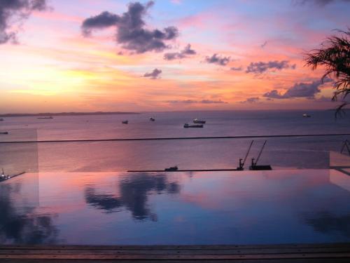 a sunset over the ocean with a swimming pool at Aram Yamí Boutique Hotel in Salvador