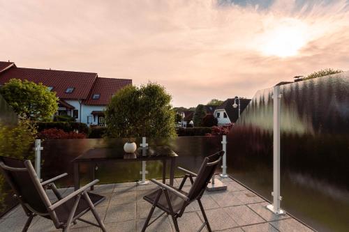 eine Terrasse mit 2 Stühlen, einem Tisch und einem Zaun in der Unterkunft Ferienwohnung Wenzlaff in Sassnitz