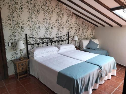 1 dormitorio con cama y pared con papel pintado en Posada La Cerra de San Roque en Santillana del Mar