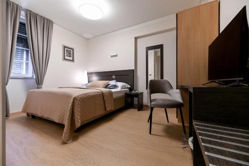 - une chambre avec un lit, une chaise et une télévision dans l'établissement Villa Hrešć S, à Zadar