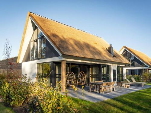 a house with a thatched roof and a patio at Luxury villa with sauna only a few minutes from the beach in De Cocksdorp