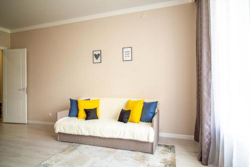 a living room with a couch with yellow and blue pillows at AB Apart Comfort 5311 in Astana