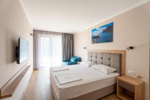ein Schlafzimmer mit einem großen Bett und einem blauen Stuhl in der Unterkunft Touch Hotel in Lozenets