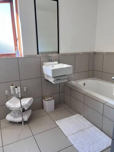 a white bathroom with a sink and a bath tub at Iyana Place in Midrand