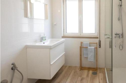 La salle de bains blanche est pourvue d'un lavabo et d'une douche. dans l'établissement Anchor House, à Albufeira
