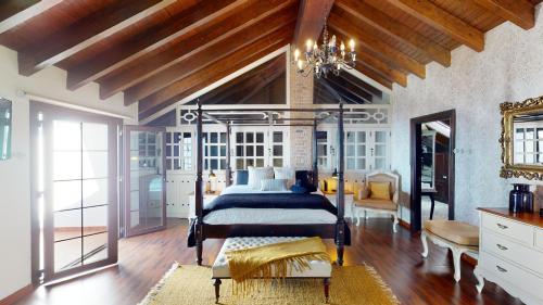 Moya的住宿－Luxury Colonial Country Villa，一间带一张床的卧室,位于带木制天花板的房间内