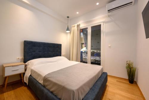 Schlafzimmer mit einem Bett mit blauem Kopfteil und einem Fenster in der Unterkunft Kukos Apartment Corfu in Kanoni